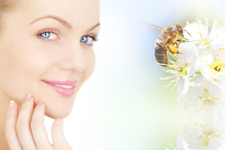 a woman with healthy skin thanking a bee for its products